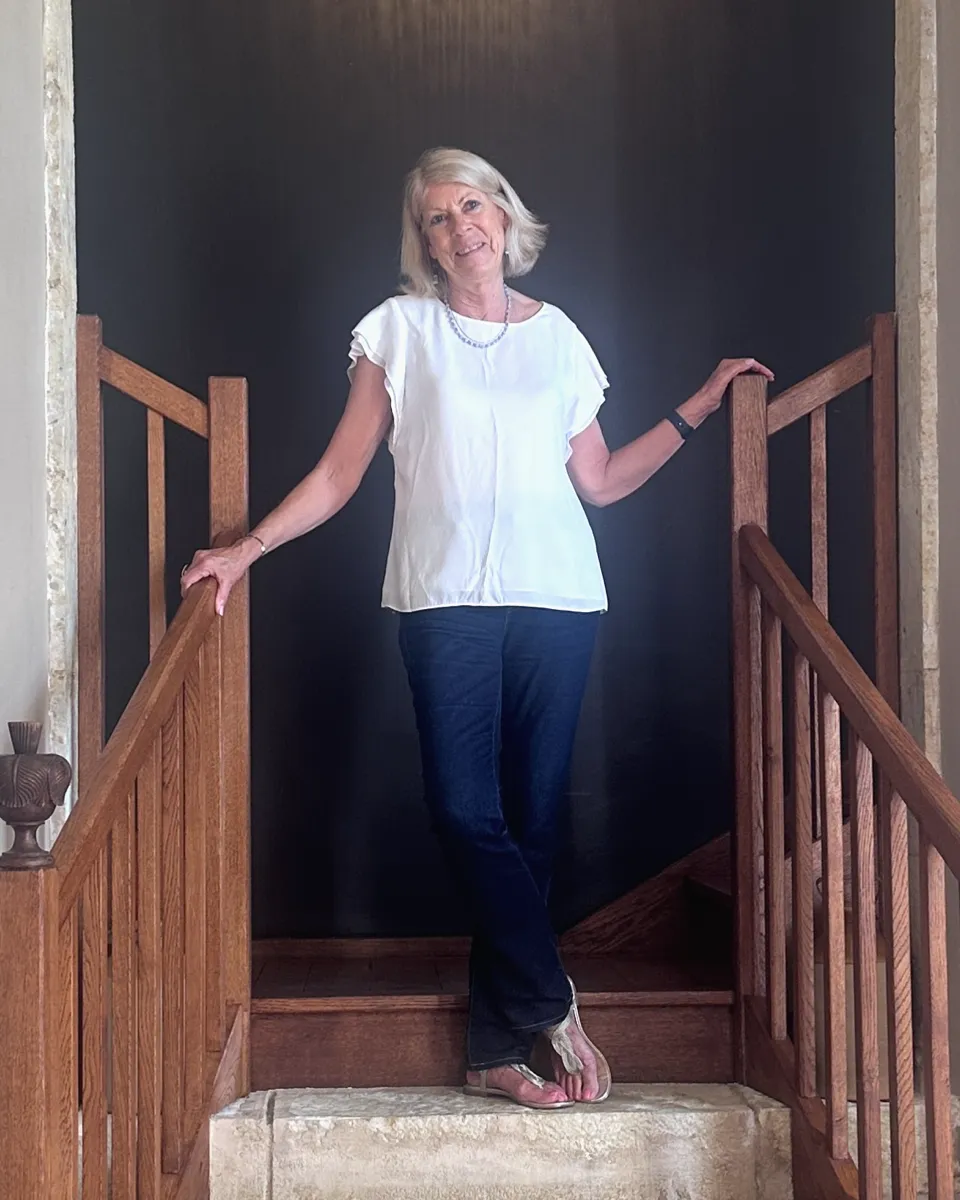 Jacqui Reich standing on a wooden staircase, smiling